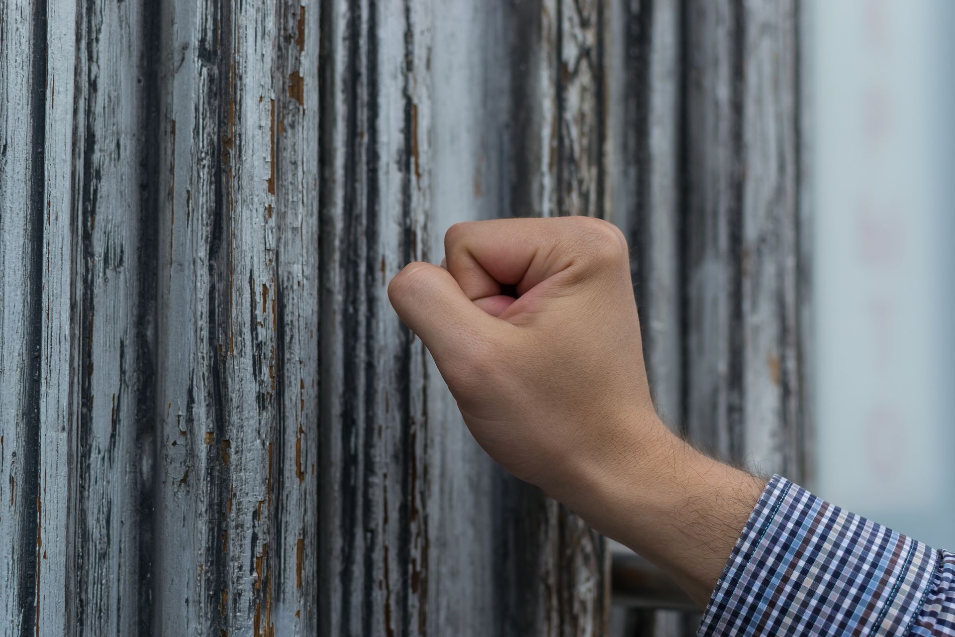 a hand knocks at the door. hand postman in a plaid shirt knocking his fist at the old and shabby front door. Anybody home. a hand knocks at the door. hand postman in a plaid shirt knocking his fist at the old and shabby front door. Anybody home.
